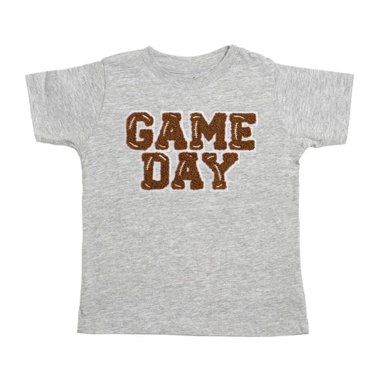 You'll score major points with the kiddos in our Grey Game Day Patch Tee! This super soft heather grey tee features a brown and white chenille patch with light grey outline, perfect for showing off their team spirit. It's tagless, topstitched ribbed collar and side seam construction make it comfy and durable to wear. Plus, each shirt is hand-pressed with child-safe inks for your peace of mind. Now, that's a winning combination!
