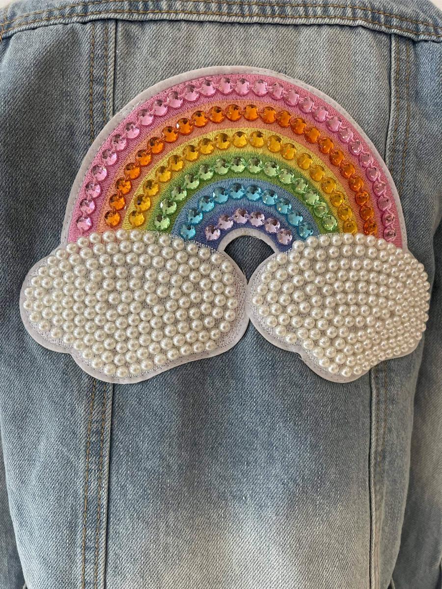 Lola + The Boys. Turn heads with this one-of-a-kind Rainbow Pearl Denim Jacket! With a light denim wash and detailed with a rainbow pearl patch on the back and rainbow buttons, this jacket will add some serious color and pizazz to any outfit. So don your outfit with the perfect jacket and make a statement!
