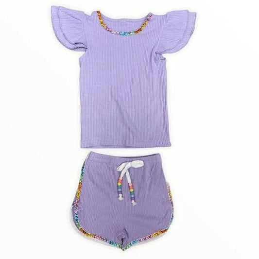 Lola + The Boys. Style up your little fashionista with this super sweet Lola + The Boys Candy Gem Bead Ruffle Set! Includes a T-shirt and matching shorts in a lovely purple hue, adorned with stylish bead embellishments on the neckline and white adjustable drawstring with beads. An easy-breezy go-to outfit!