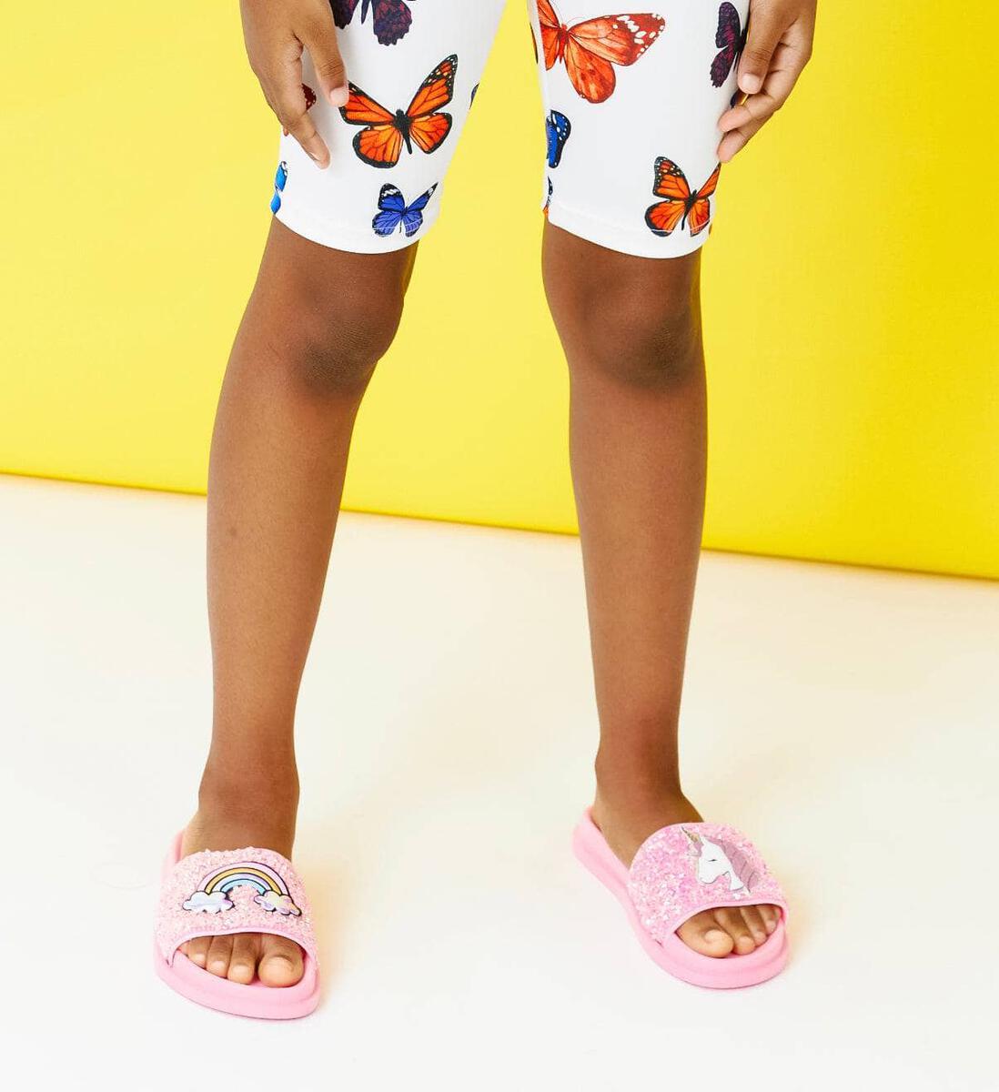 Lola + The Boys. Step into style in these Lola + The Boys Pink Glitter Unicorn Slides. Bubblegum pink glitter slides with unicorn and rainbow rubber embellishments on the tops of both feet! On the run shoes, perfect for everyday wear. 