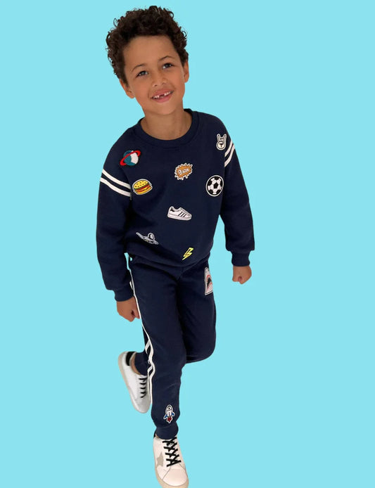 Stay sporty and keep it cute with this Lola + The Boys Varsity Patch Jogger Set in Navy! Features a pullover sweatshirt and matching jogger with assorted patches and varsity stripe detail. This soft set is the easiest go-to outfit.   100% Cotton. Machine washable. Tumble dry low. 